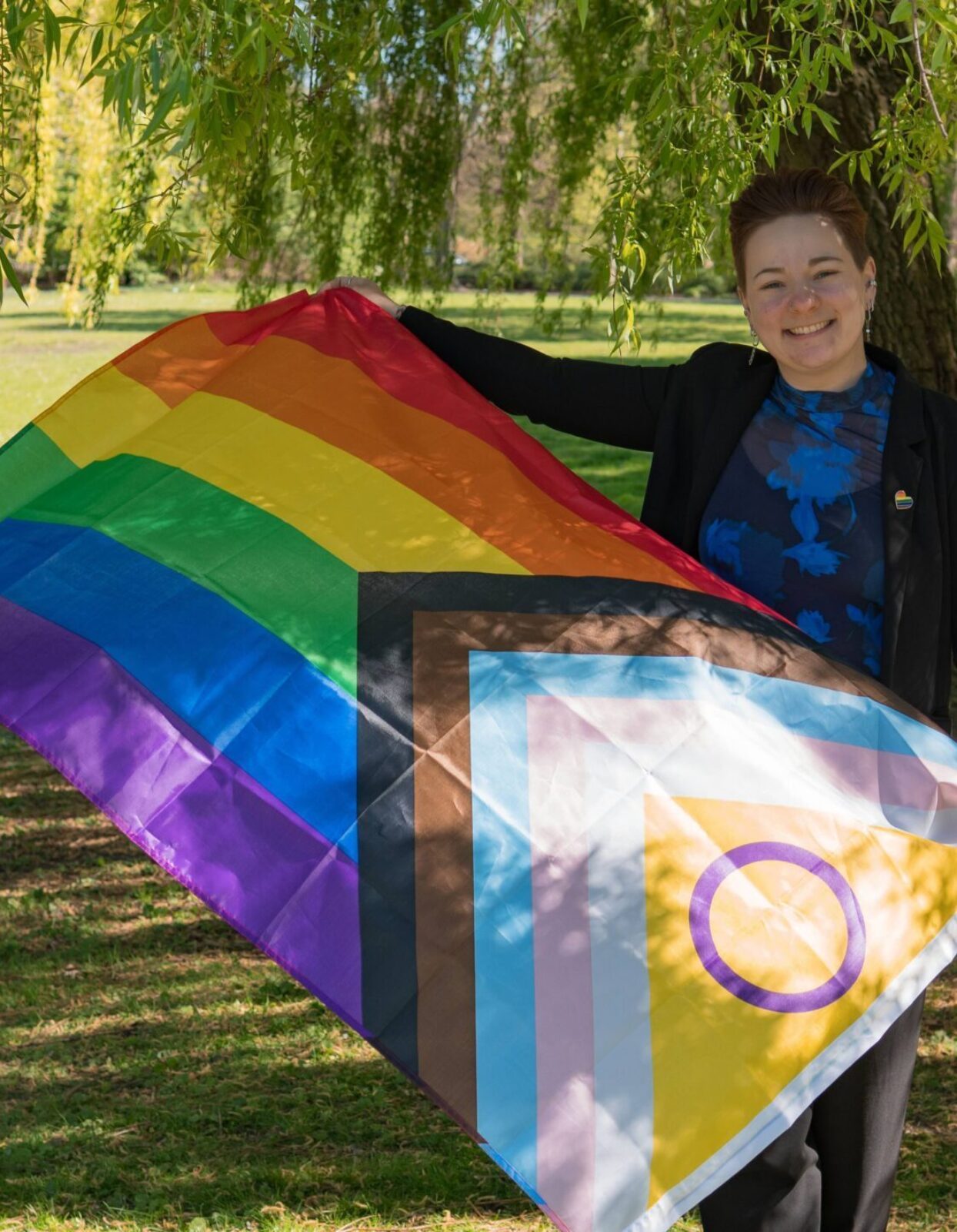 Freie Rednerin hält die progressive Regenbogen Flagge hoch und lächelt