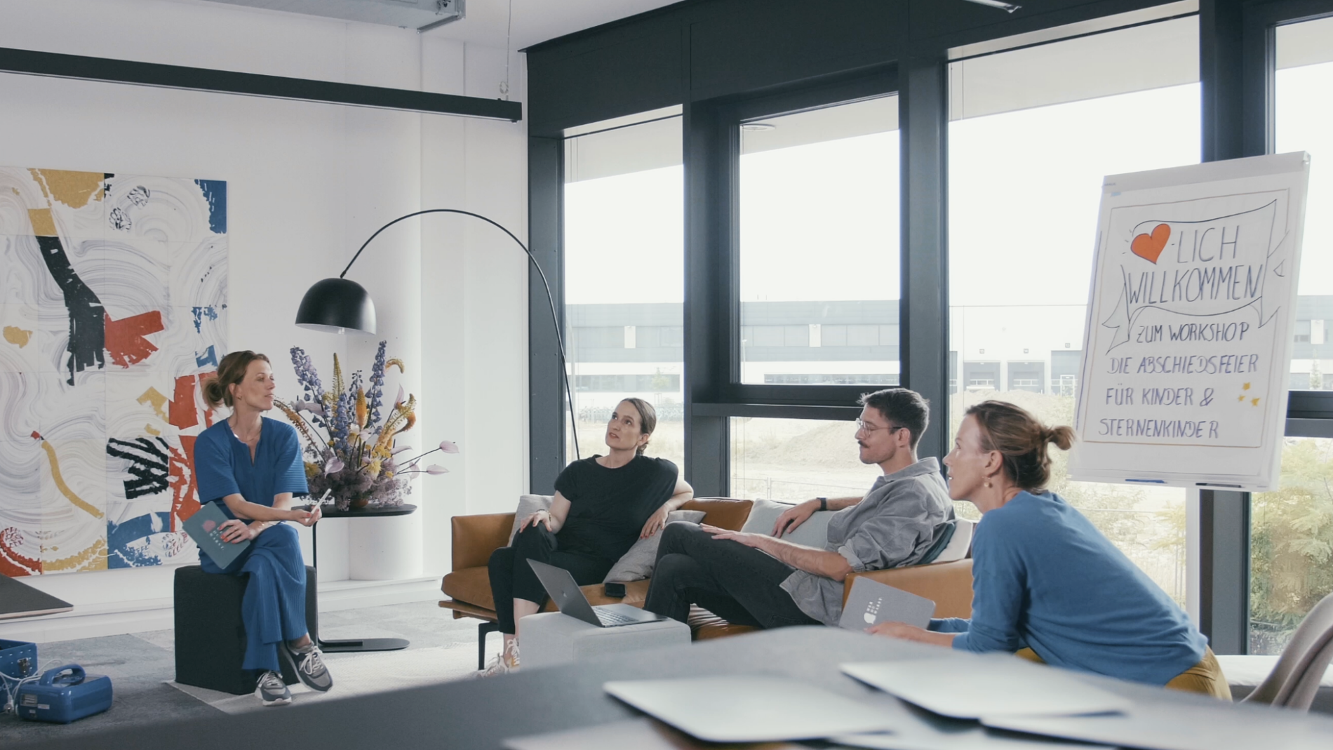 Weiterbildung Trauerredner (2) Alle Wer DU Warst Masterclass Expert*innen sitzen zusammen im Ship in Köln und unterhalten sich Mel Breese Carina Fritz Benni Bauerdick und Gunda Tibelius sind im Bild im Hintergrund ein Flip Chart auf dem Steht Herzlich willkommen zum Workshop Abschied nehmen von Kindern und Sternenkindern