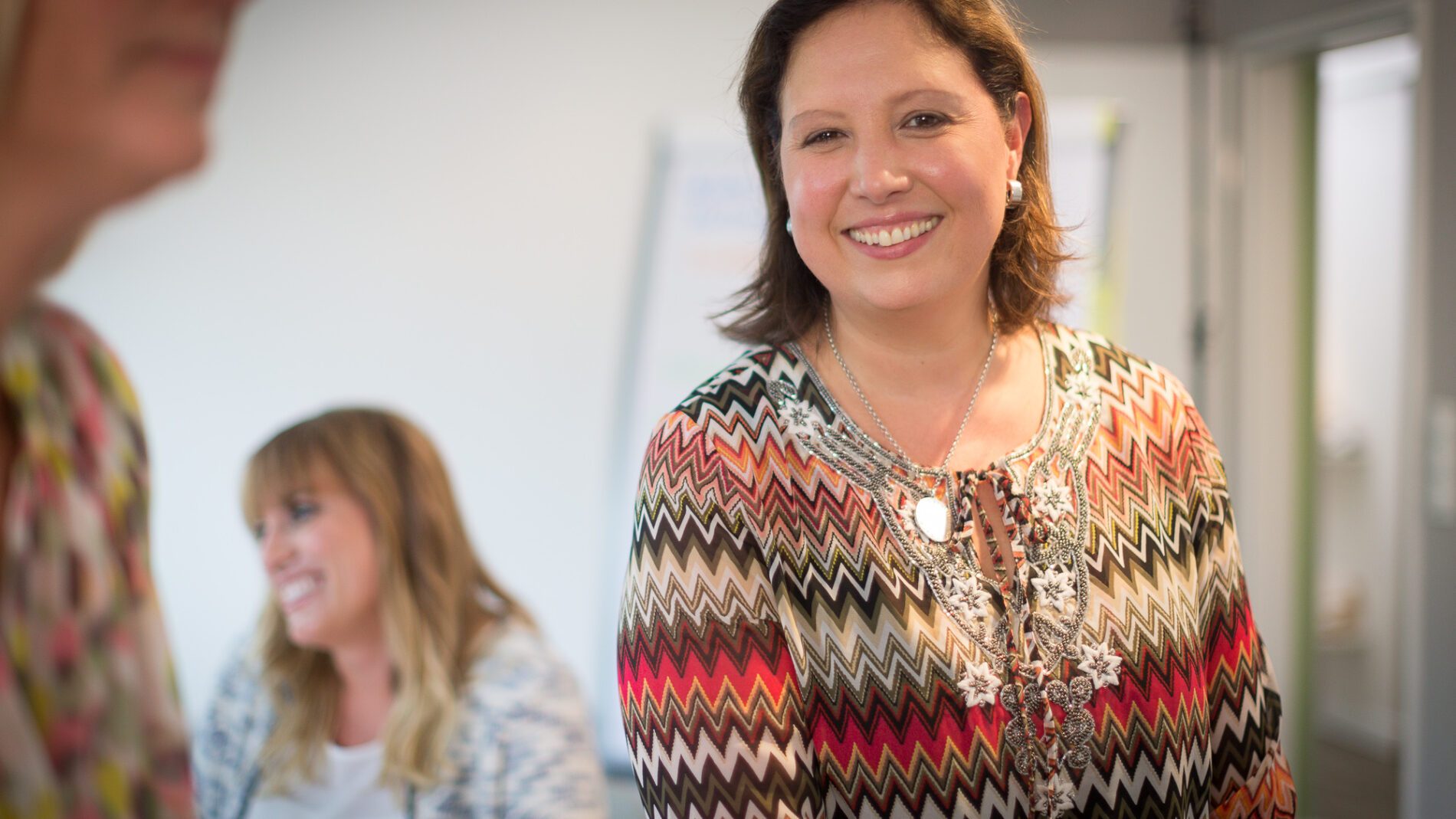 Natalie Katia Greve unsere Expertin für Trauerbegleitung in bunt gemustertem Oberteil lächelt in die Kamera