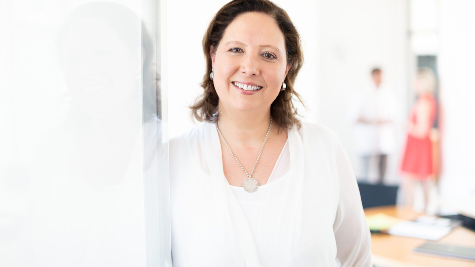 Trauerbegleiterin Natalie Katia Greve im Portrait lächelt in die Kamera ganz in weiß gekleidet mit weißem Hintergrund.