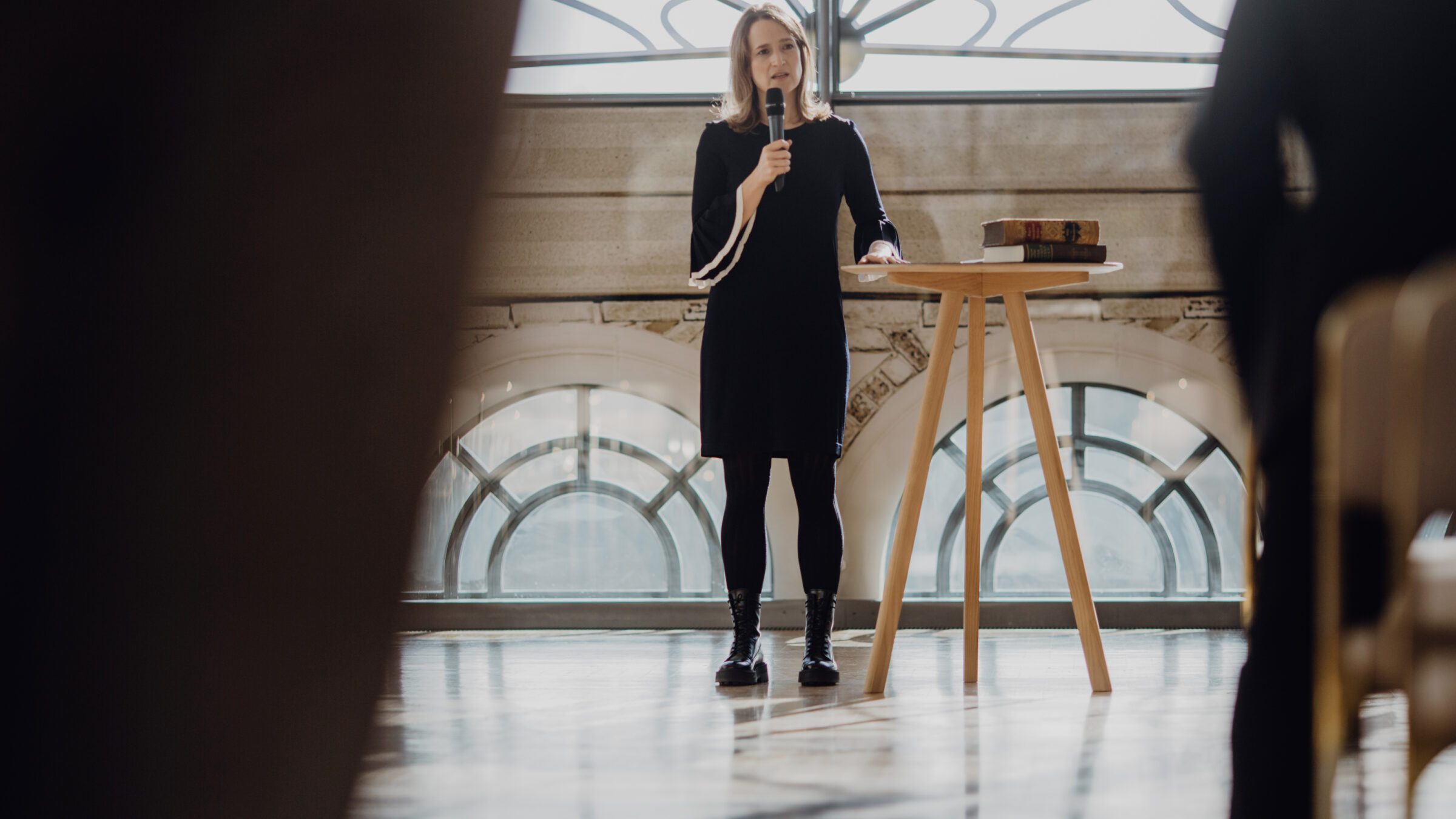 Rednerin Carina Fritz hält eine Trauerrede in der Flora man sieht sie aus einiger Entferung ihre Rede halten mit Mikrofon